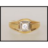 A stamped 750 18ct gold signet ring set with a round cut white stone within a white gold square head