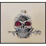 A stamped 925 silver pendant necklace in the form of a skull having ruby stone eyes and a rose in
