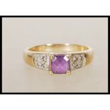 A 9ct gold English hallmarked ring set with a central square cut purple stone flanked with