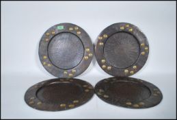 A group of four Arts and Crafts style brass centrepiece plates having hand beaten geometric