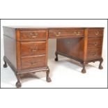 A mid 20th Century mahogany twin pedestal breakfront kneehole desk having leather insert top with