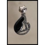 A stamped 925 silver brooch in the form of a seated cat having a marcasite body with a onyx back and