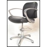 A pump action chrome and black leather salon barbers desk chair having chromed boomerang arm