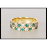 A stamped 18ct gold eternity ring set with two rows of alternate round cut diamond and emerald