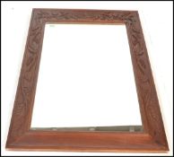 A large carved fruit wood wall hanging mirror, central mirror panel framed within a frame carved