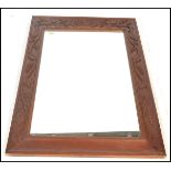 A large carved fruit wood wall hanging mirror, central mirror panel framed within a frame carved