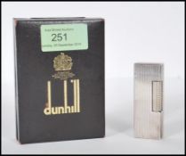 A vintage mid 20th Century Dunhill white metal rollagas lighter of reeded form, within original