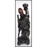 A 20th Century Chinese carved hardwood figure in the form of Shou-Lao bearing a scroll and raised on