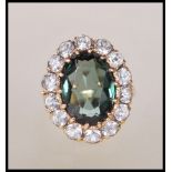 A stamped 9ct gold ring set with a oval cut green stone with a halo of white stones in a
