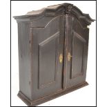 An 18th Century Dutch Georgian ebonised pine hanging wall cabinet, the arched top above a pair of