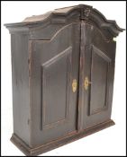 An 18th Century Dutch Georgian ebonised pine hanging wall cabinet, the arched top above a pair of