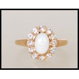 A hallmarked 9ct gold ring set with a central oval cabochon with a halo of white stones.