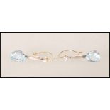 A pair of ladies gold drop earrings set with oval cut aquamarine stones with round cut diamonds