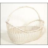 A vintage 20th Century wicker moses / laundry basket being painted in white, of large proportions