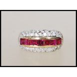 A stamped 9ct gold ladies dress ring set with a central row of square cut red stones surrounded by