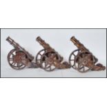 A set of three vintage 20th Century cast metal fireside cannons having a lustre finish, each set