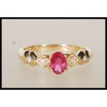 A hallmarked 9ct yellow gold ring having central oval faceted cut pink stone flanked by white accent