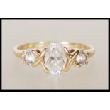 A stamped 585 14ct gold ring set with a central oval cut white stone flanked by two round cut