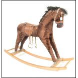 A 1960s rocking horse with brown plush hair and a painted wooden muzzle saddle and stirrups raised