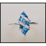 A hallmarked 9ct white gold ring having prong set lozenge shape blue stone with overlapping illusion