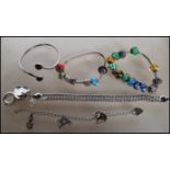 A selection of silver bracelets to include two snake chain bracelets having beaded charms, a cuff