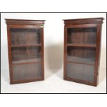 Two 20th Century hardwood apothecary / display wall mounted cabinets having sectional glazed doors