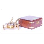 A 20th Century cased brass sundial compass of metamorphic design with compass to base with folding