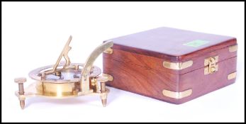 A 20th Century cased brass sundial compass of metamorphic design with compass to base with folding