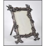 A silver white metal picture frame molded in the form of textured tree trunks with branch accents.