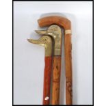 A group of three vintage 20th Century walking stick canes, two having brass duck head handles, the