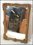 A 19th Century rococo style gilt wall mirror having raised gesso scrolled and scallop shell