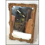 A 19th Century rococo style gilt wall mirror having raised gesso scrolled and scallop shell