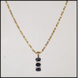 A stamped 375 9ct gold necklace having a pendant set with three oval cut sapphires with white accent