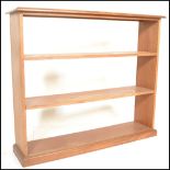 A 20th Century solid walnut open bookcase having three shelves raised on a plinth base.