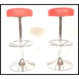A pair of vintage bar bistro stools raised on central chromed columns terminating in round bases
