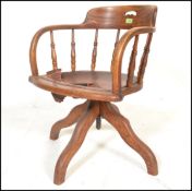 An early 20th Century Edwardian oak captains chair raised on quadruped base with turned rail