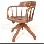 An early 20th Century Edwardian oak captains chair raised on quadruped base with turned rail