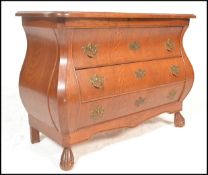 A 20th Century French style oak bombe chest of drawers consisting of three long drawers below flared