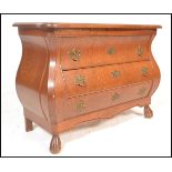 A 20th Century French style oak bombe chest of drawers consisting of three long drawers below flared