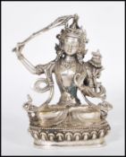 A 20th Century Tibetan white brass figure of Bodhisattva Manjushri seated crossed legged on a