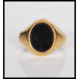 A stamped 375 9ct gold signet ring having an oval cut black stone panel to the head. Weight 4.5g.