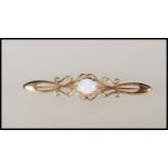 A hallmarked 9ct gold bar brooch having scrolled decoration set with a central opal cabochon.