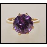 A hallmarked 9ct yellow gold ring having a large round cut purple stone, prong set on a decorative