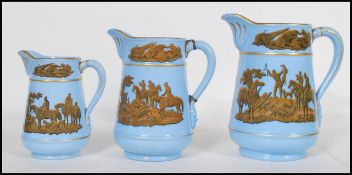 A group of three 19th Century graduating prattware pitcher jugs having blue grounds with transfer