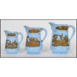 A group of three 19th Century graduating prattware pitcher jugs having blue grounds with transfer