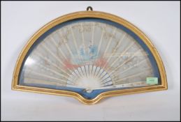 An early 20th Century 1920's hand painted fan depicting a lady and gentleman with gilt scrolled