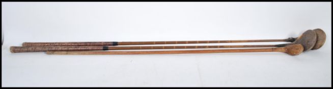 A group of three vintage early 20th Century golf clubs by Auchterlonie having faux cane shafts to