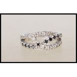 A stamped 925 silver ring of crossover design set with white and black diamonds. Weight 3.4g. Size