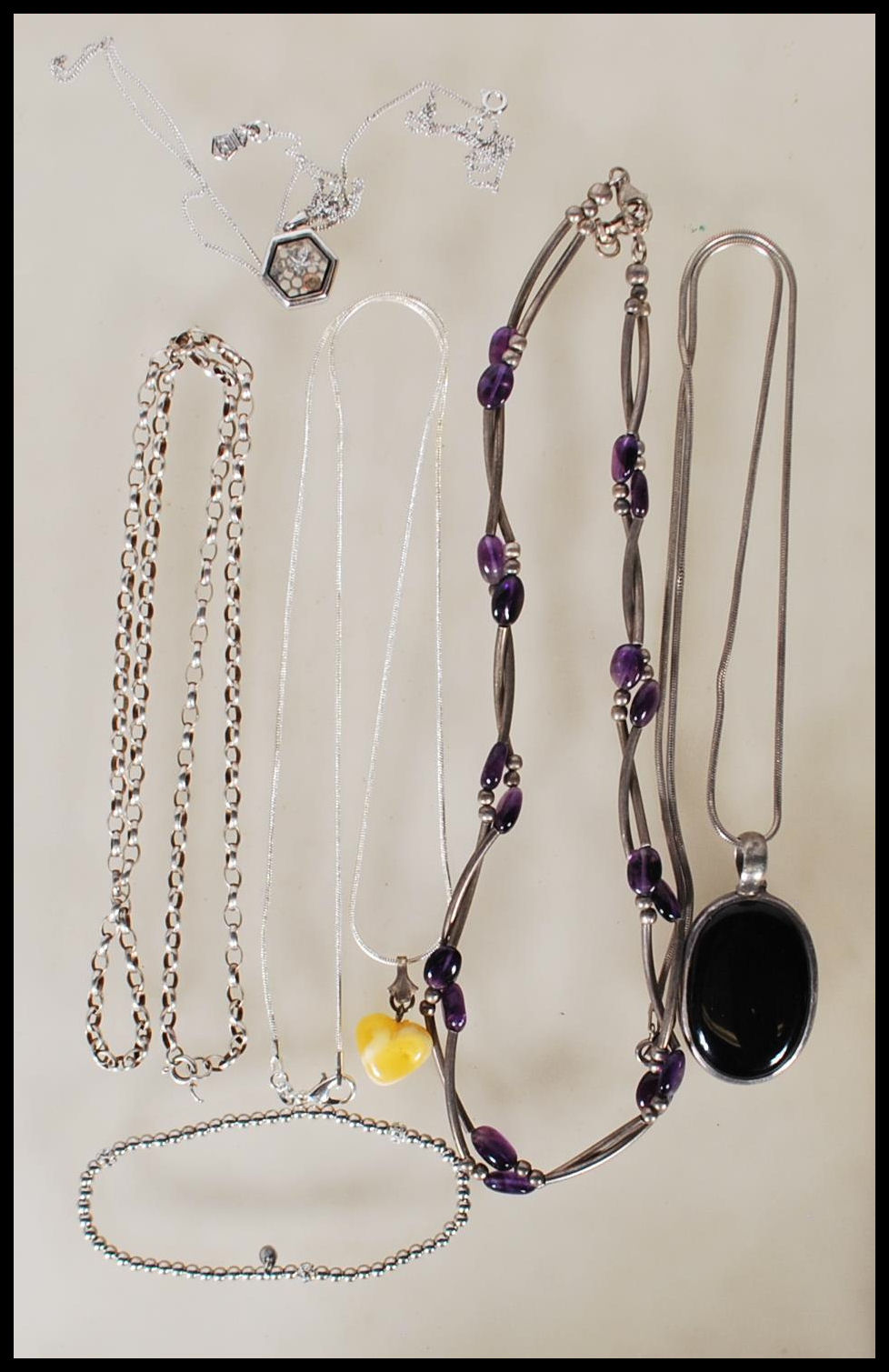 A selection of silver necklaces to include a spacer necklace with purple beads, a snake chain