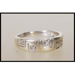 A hallmarked 9ct gold ring set with with five diamonds on a greek key style tapering mount.